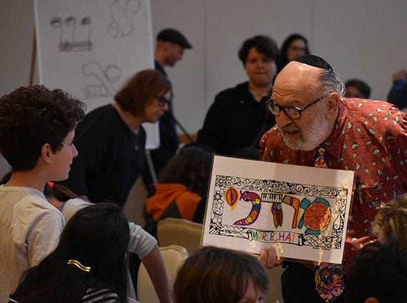 man holding a sign with Hebrew letters on it, showing it to children