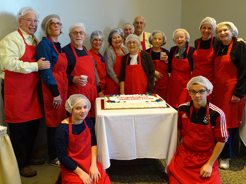 people in red aprons and hairnets at a hunger project event