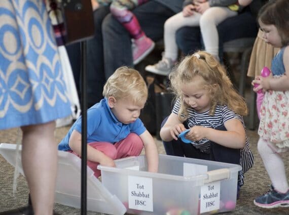 two toddlers pull musical instruments out of a container at tot shabbat
