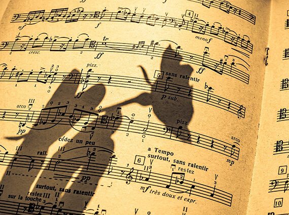 shadow of hand holding flower over sheet music