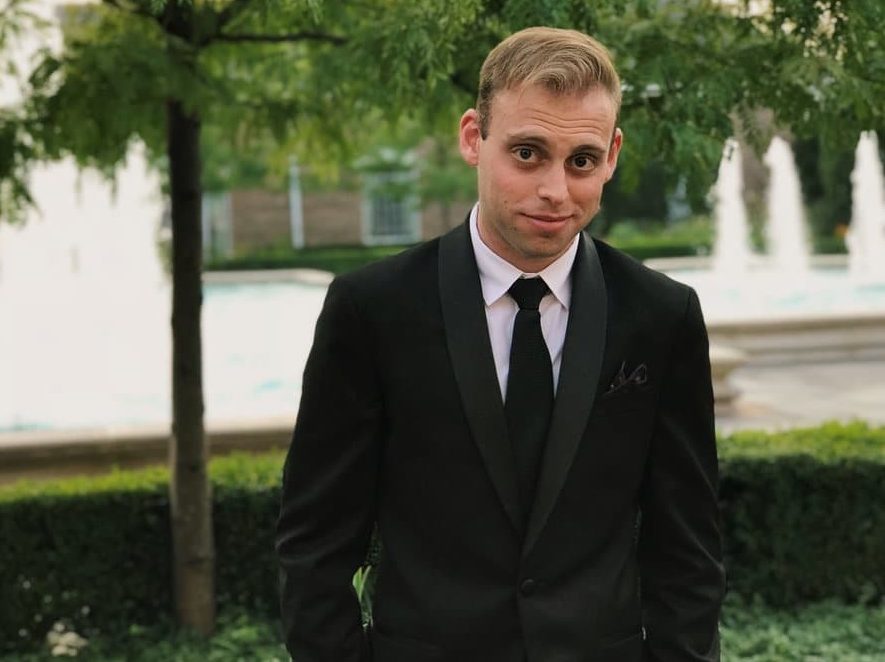 Jacob Spike Kraus in black suit, white shirt, standing outside