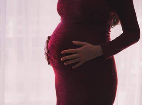 Photo of pregnant person with hands on their belly