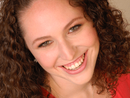 Curly haired woman smiling, wearing red blouse in closeup