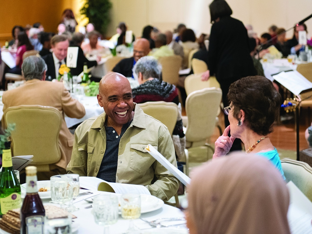 Black man smiling and talking with white woman at Passover table