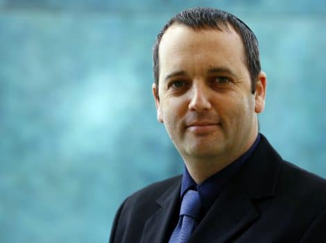 Gilad Kariv in front of blue background