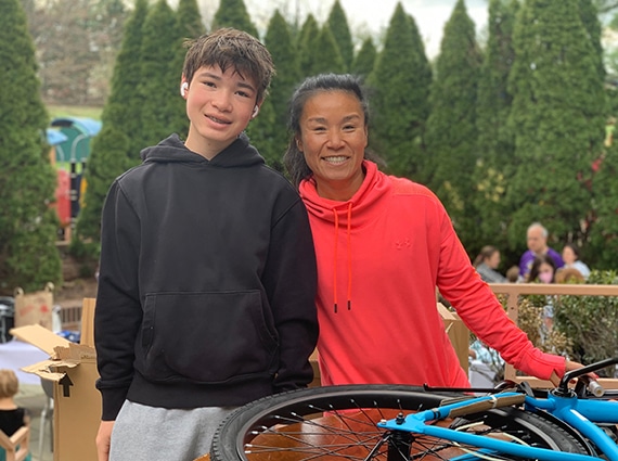 Mother and teenage son smiling with bicycle they helped refurbish for a child in need.