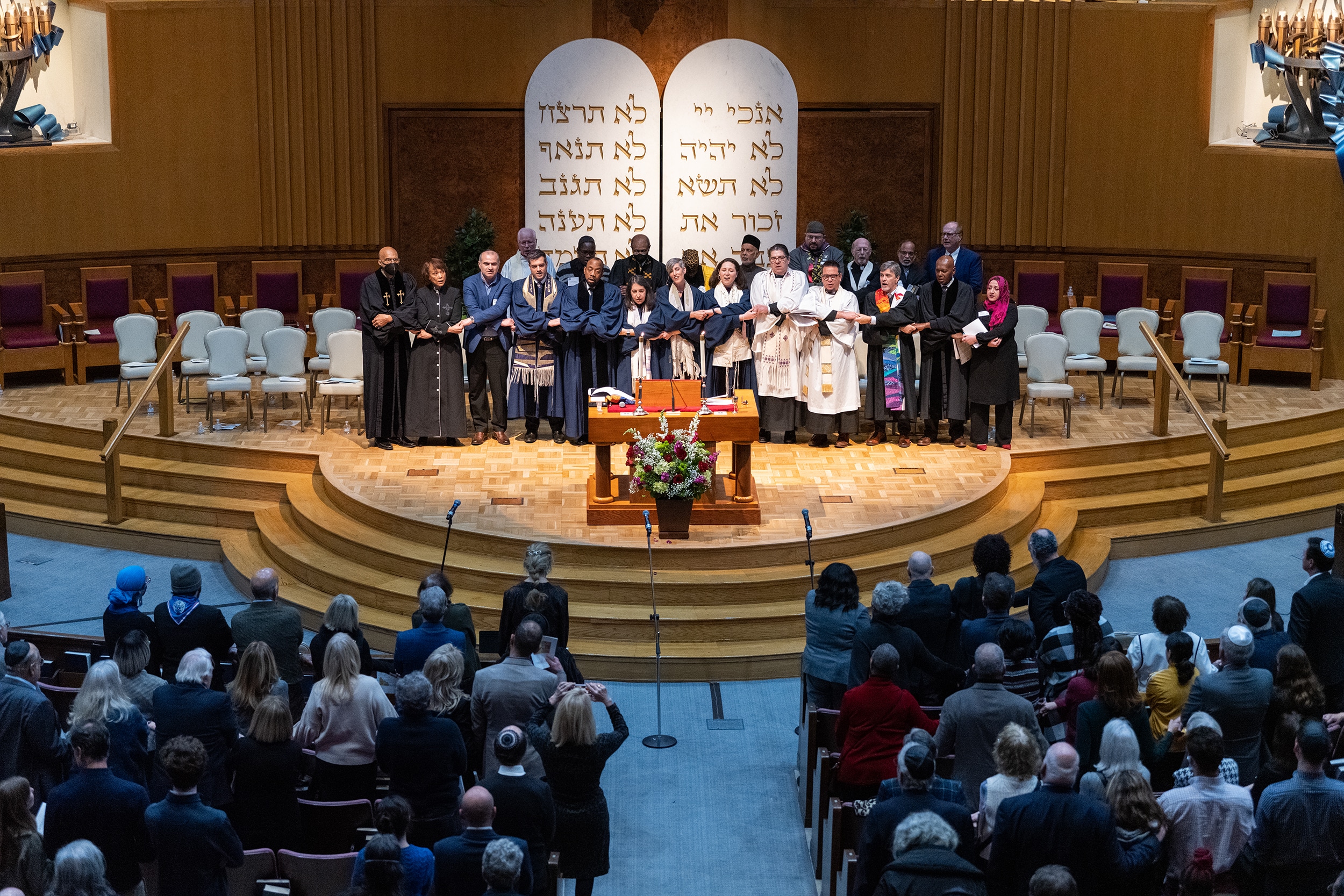 Clergy of various faiths join hands on the bima for MLK Shabbat 2023.