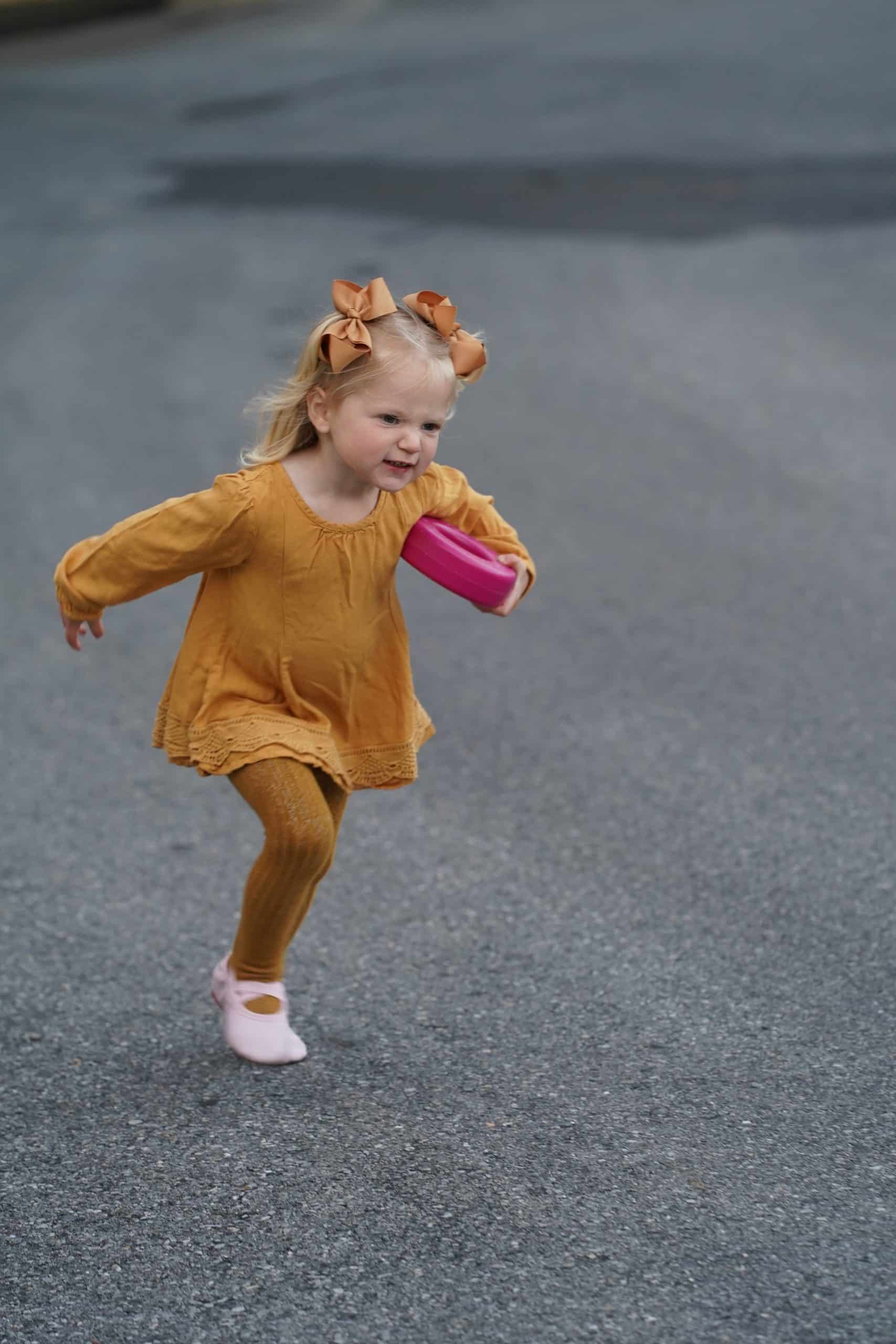 Toddler in costume runs across the parking lot