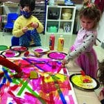 two children work on an abstract art piece