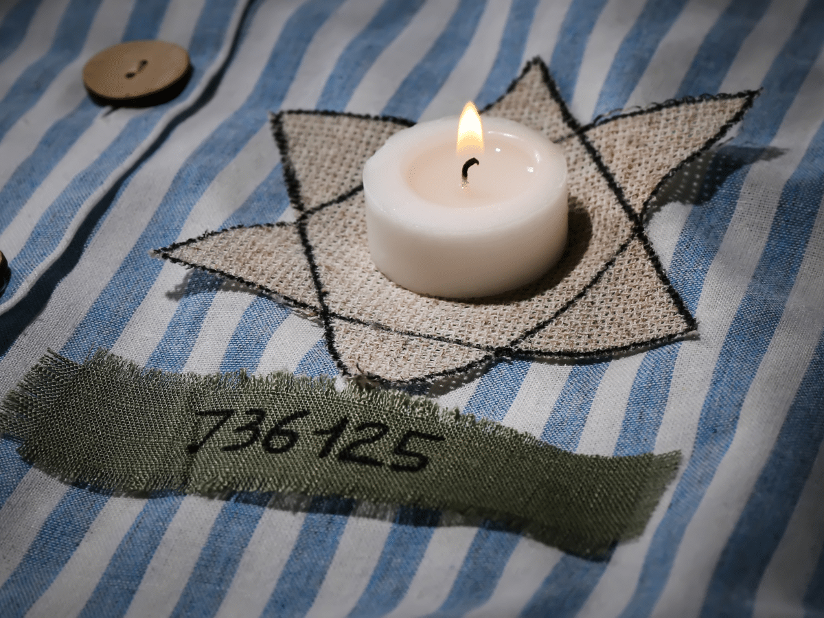 candle on replica concentration camp uniform with Star of David stitched on
