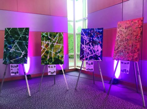 4 abstract art pieces sit on easels as part of a display