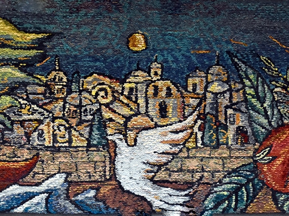 closeup of tapestry with dove in center in front of Jerusalem Old City