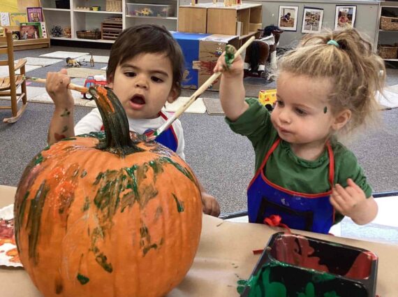 Two young children painting a pumpkin