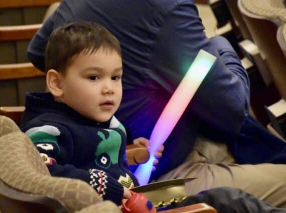 Young child with a glowing stick for shabbat hanukkah 2023