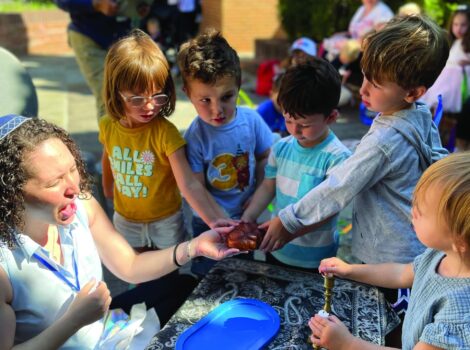 Children stand around a table holding a challah.