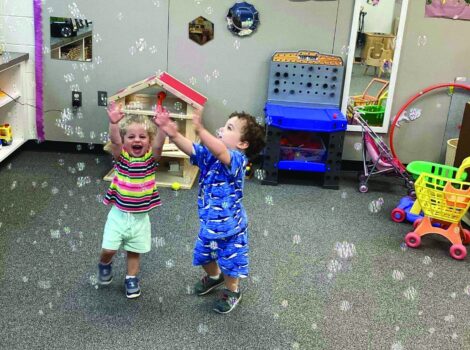 Two young children play with bubbles
