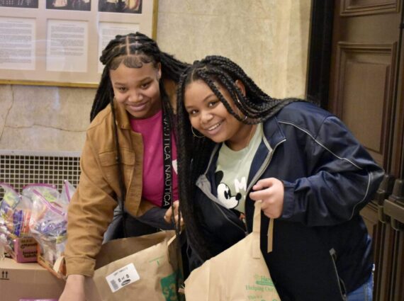 two Black girls pack bags of food