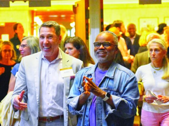 White man in sportcoat stands next to Black man in denim shirt and kippah.