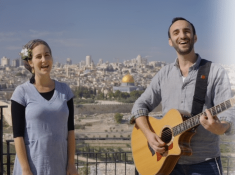 Woman stands next to a man with a guitar overlooking Jerusalem