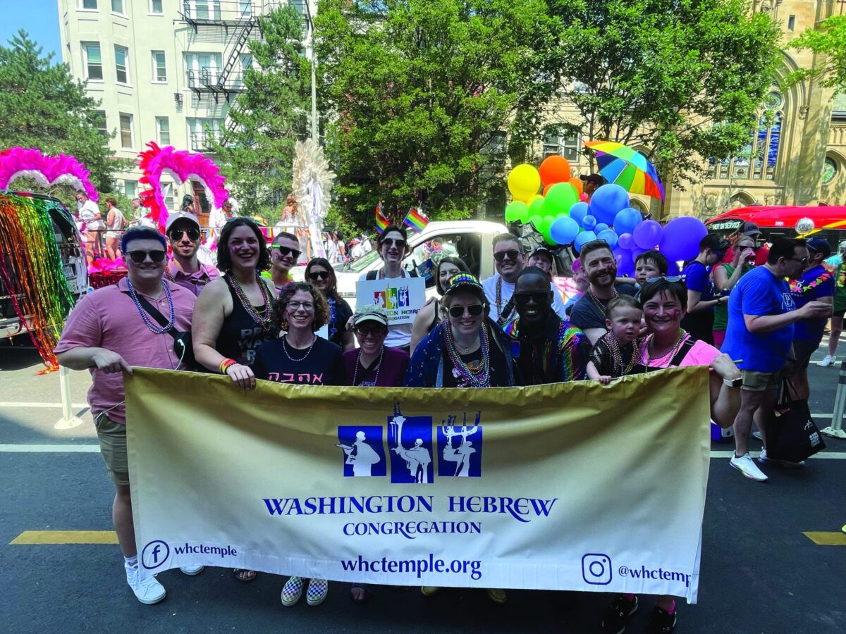 WHC members in rainbow accessories behind the WHC banner at the 2023 Capital Pride Parade
