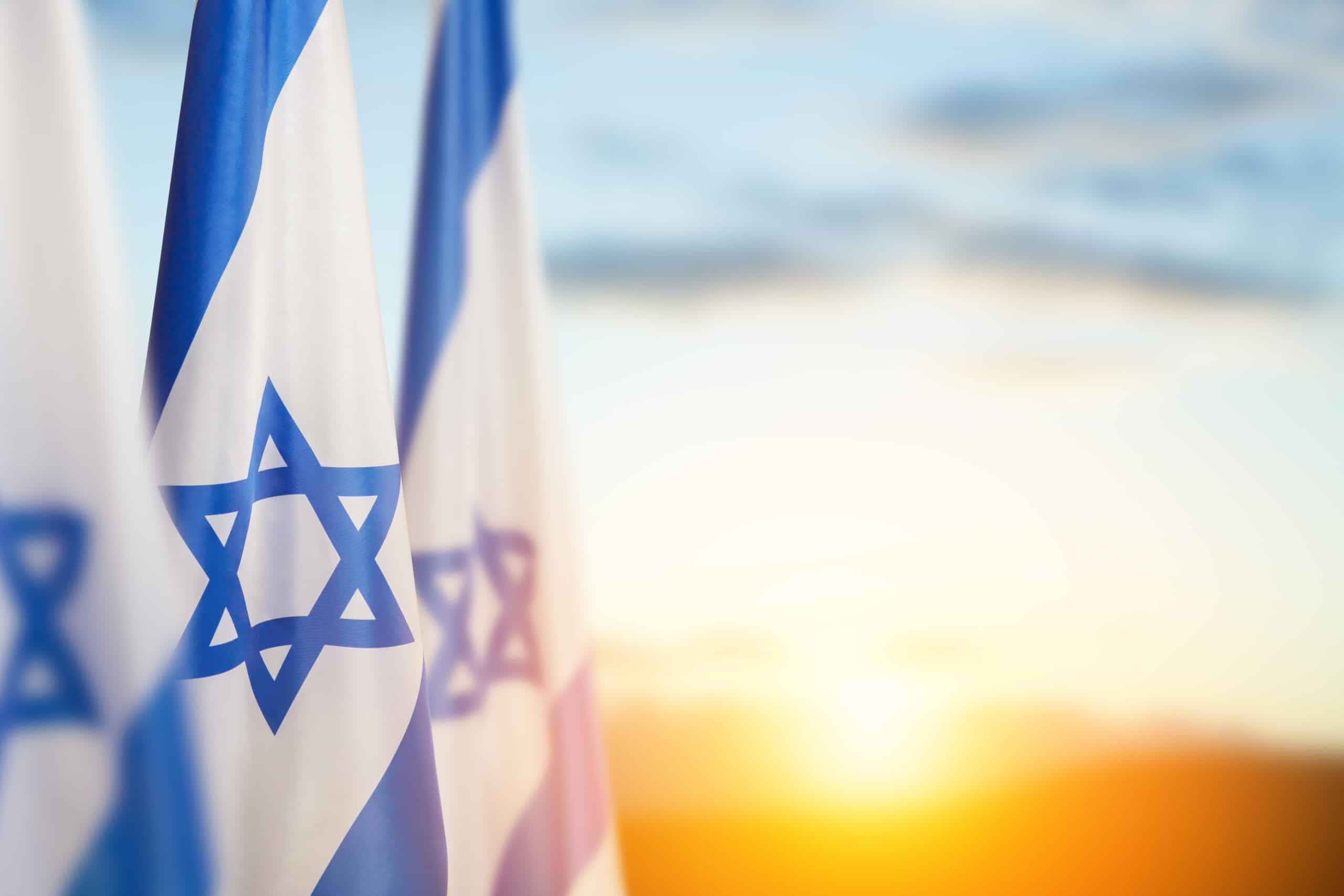 Israel flags with a star of David over sunset