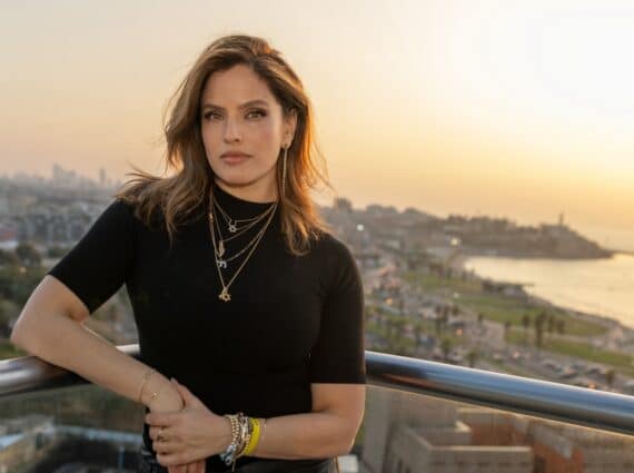 Noa Tishby stands on a balcony overlooking the ocean