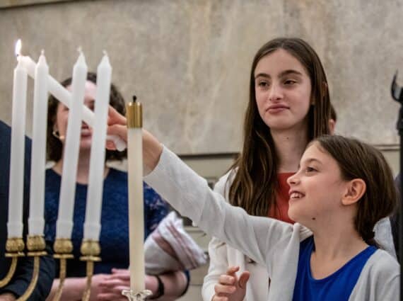 girl lighting hanukkah candles