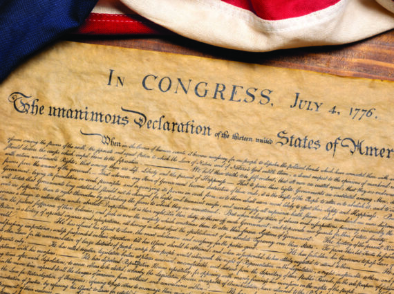 Declaration of Independence on parchment with US flag draped over the top