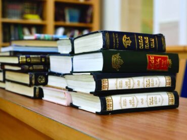 Stack of books on a table with Hebrew titles on the spines