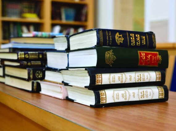 Stack of books on a table with Hebrew titles on the spines