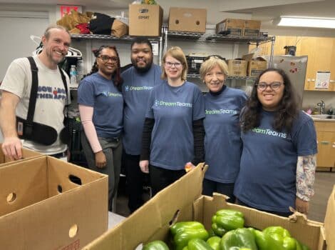 Six people wearinig blue DreamTeam t-shirts as they volunteer packing vegetables