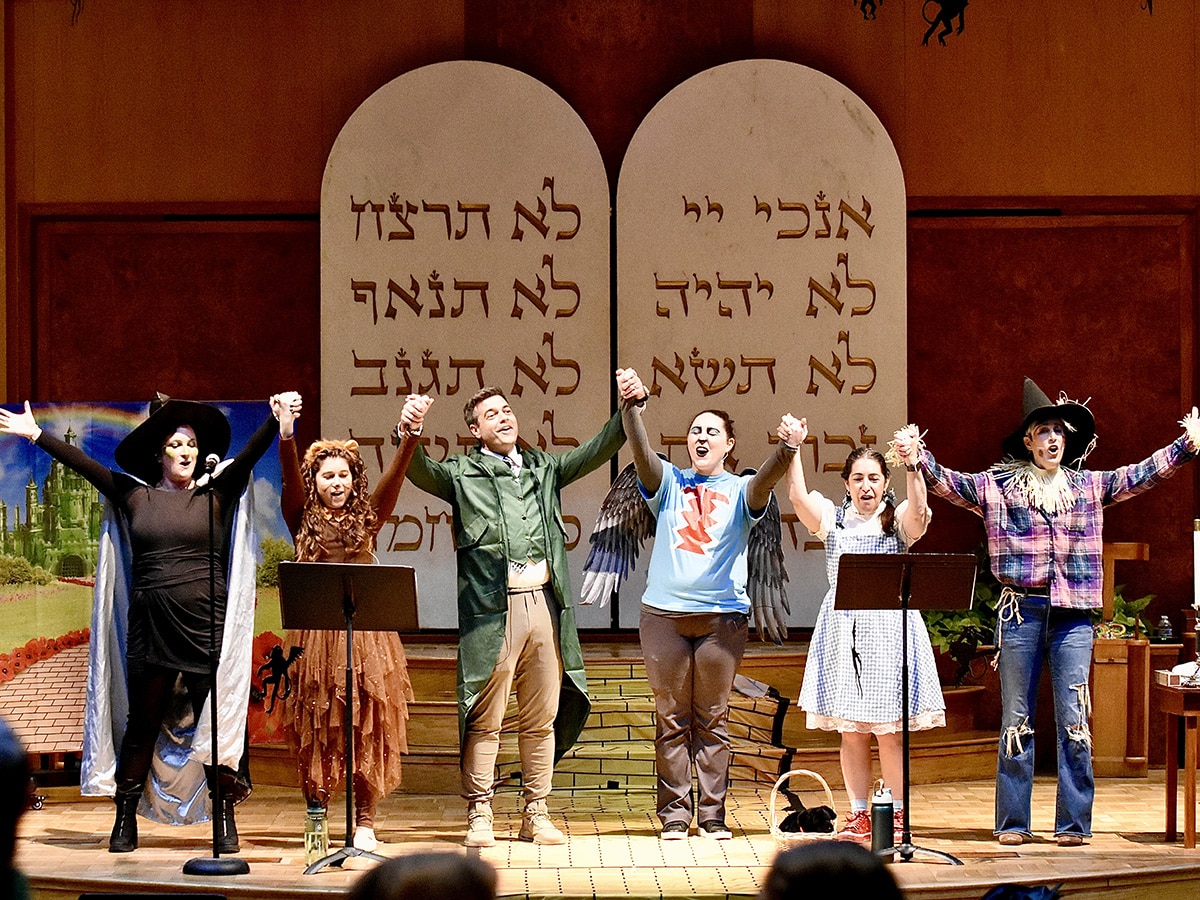 Clergy in Wizard of Oz themed costumes with hands upraised during Purim in Oz