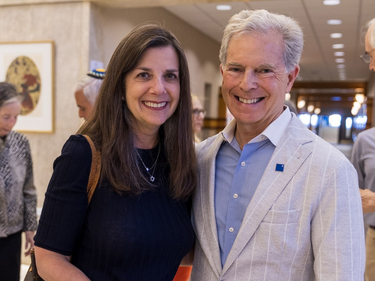 Woman with long black hair stands next to man with gray hair in a gray suit